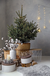 Photo of Little Christmas tree with fairy lights in bedroom interior