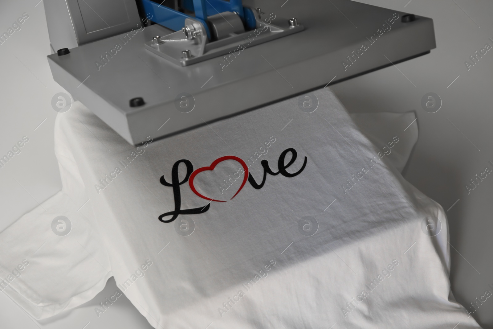 Photo of Printing logo. Heat press with t-shirt on white table