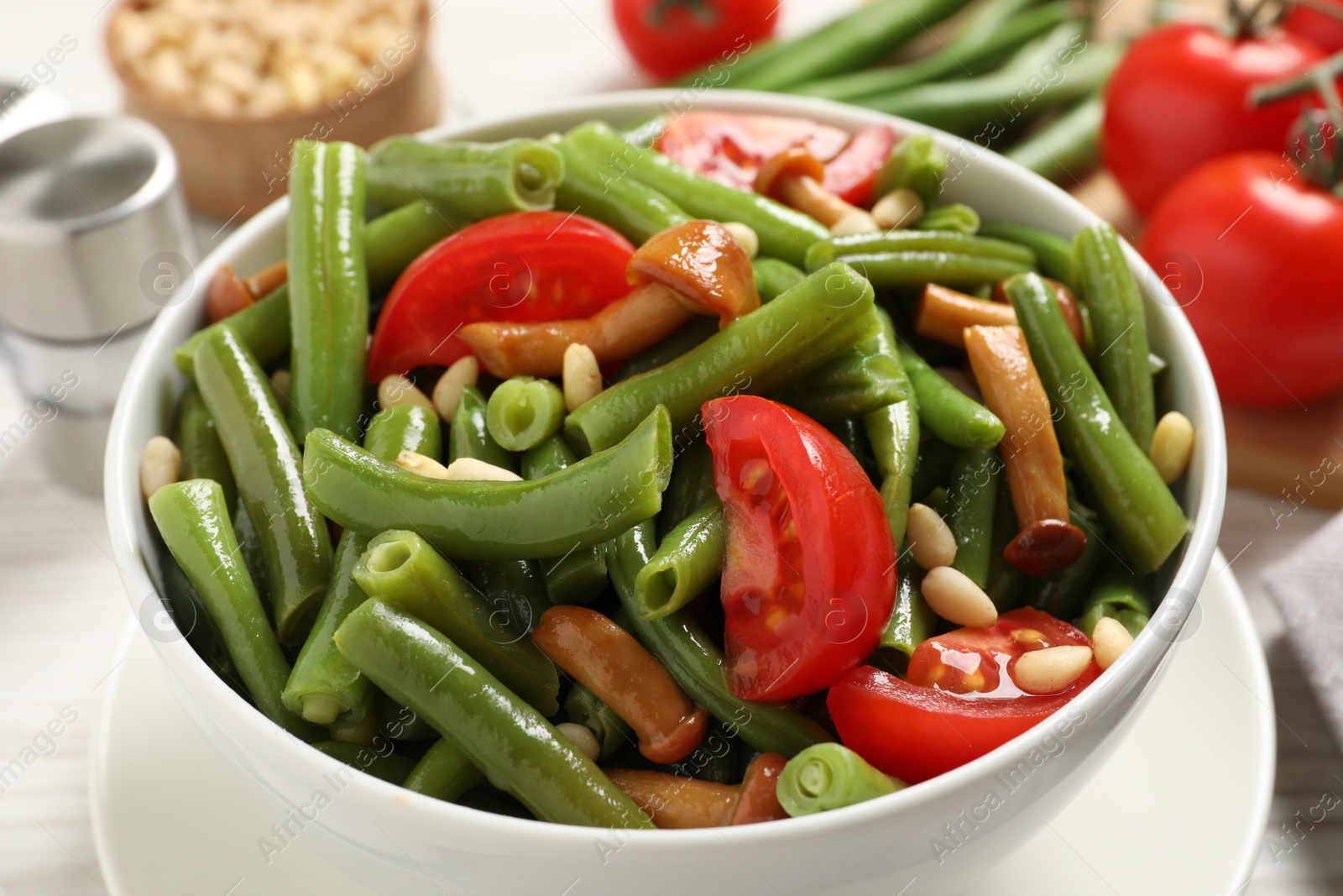 Photo of Delicious salad with green beans, mushrooms, pine nuts and tomatoes on table, closeup
