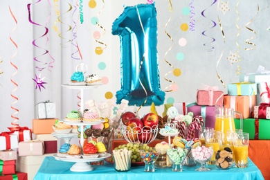 Dessert table in room decorated with blue balloon for 1 year birthday party