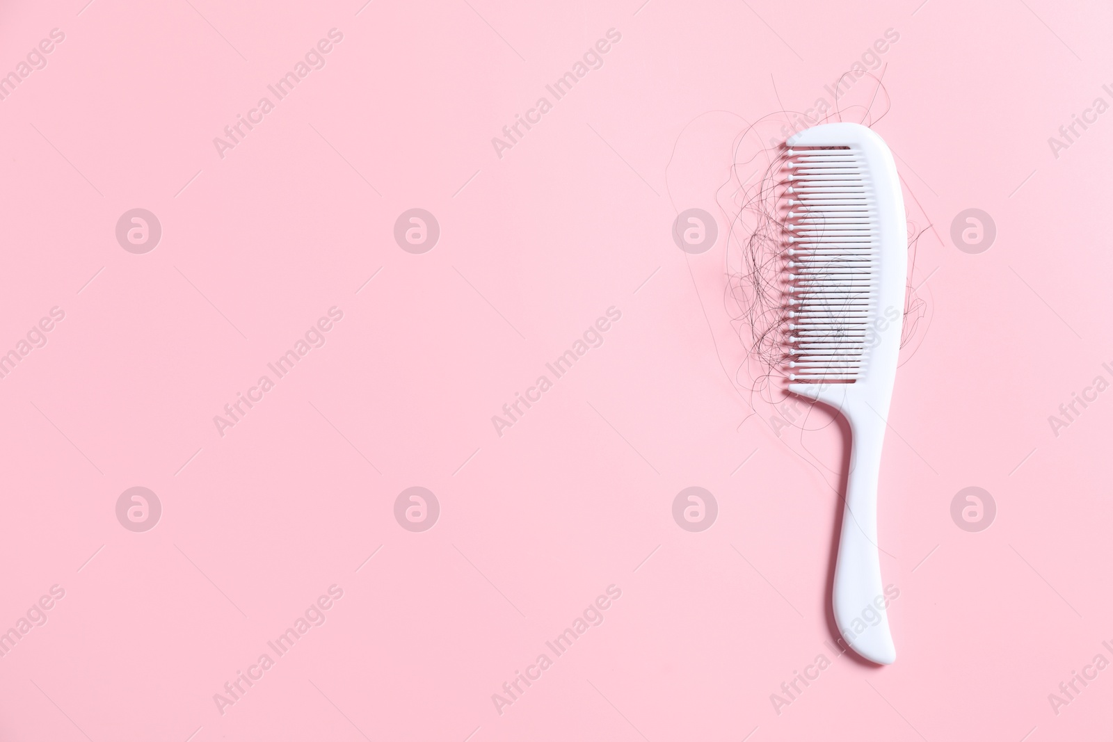 Photo of Comb with lost hair on pink background, top view. Space for text