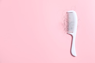 Photo of Comb with lost hair on pink background, top view. Space for text