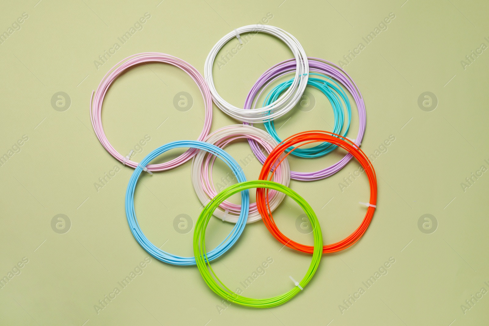 Photo of Colorful plastic filaments for 3D pen on olive background, flat lay