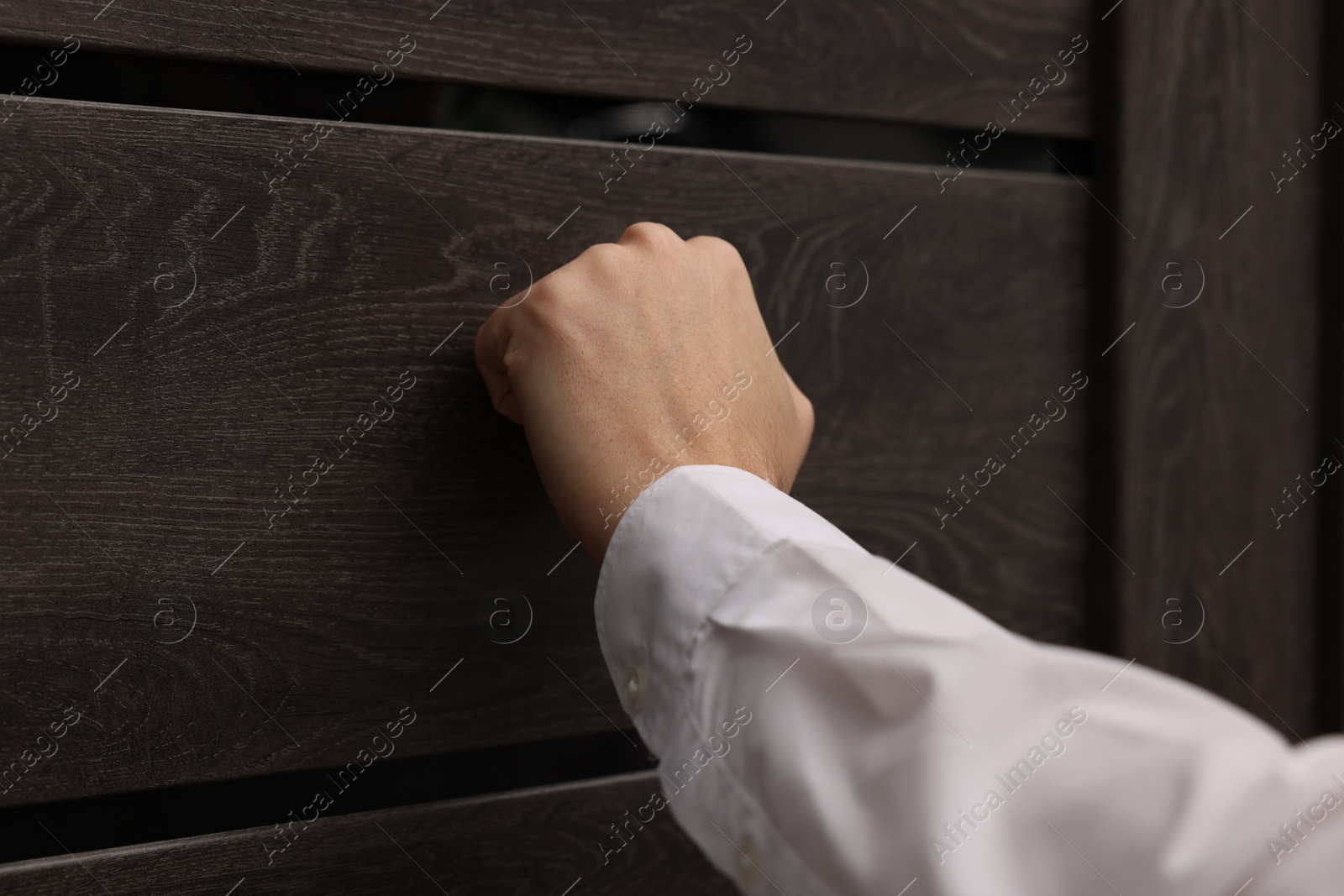 Photo of Collector knocking on door indoors, closeup view