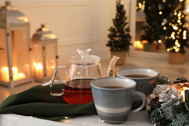 Photo of Aromatic tea on white table in room decorated for Christmas