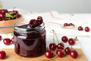 Photo of Jar of pickled cherries and fresh fruits on table, closeup