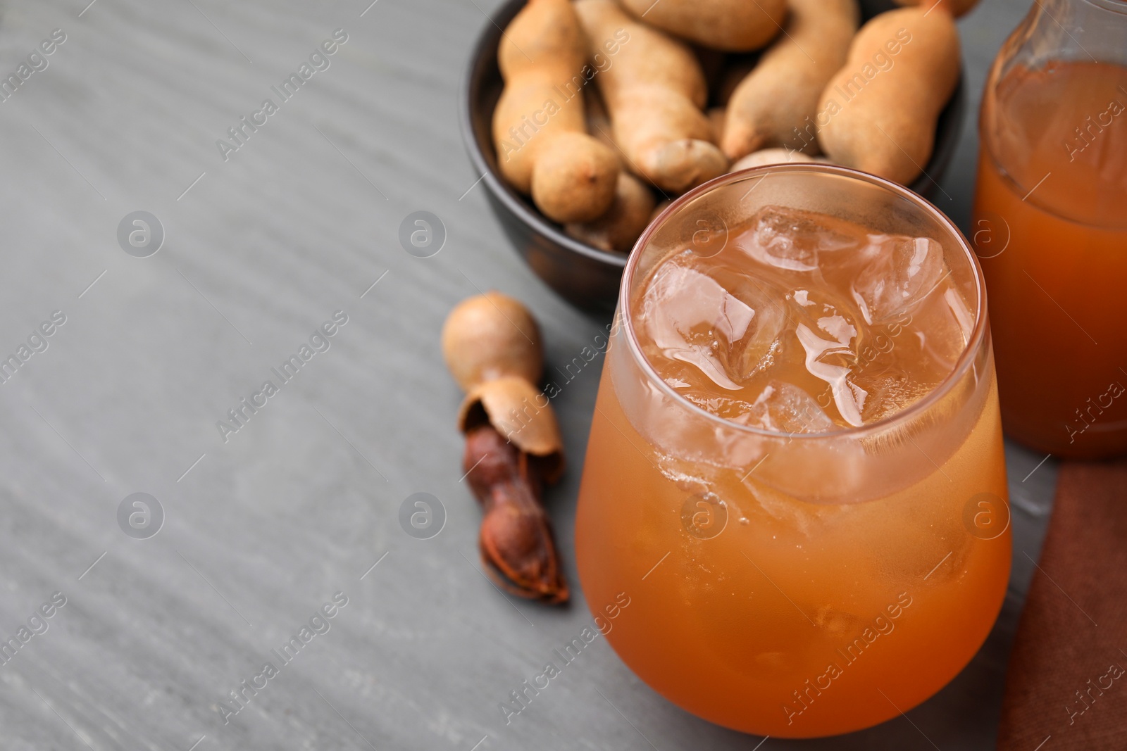 Photo of Freshly made tamarind juice on grey wooden table, closeup. Space for text