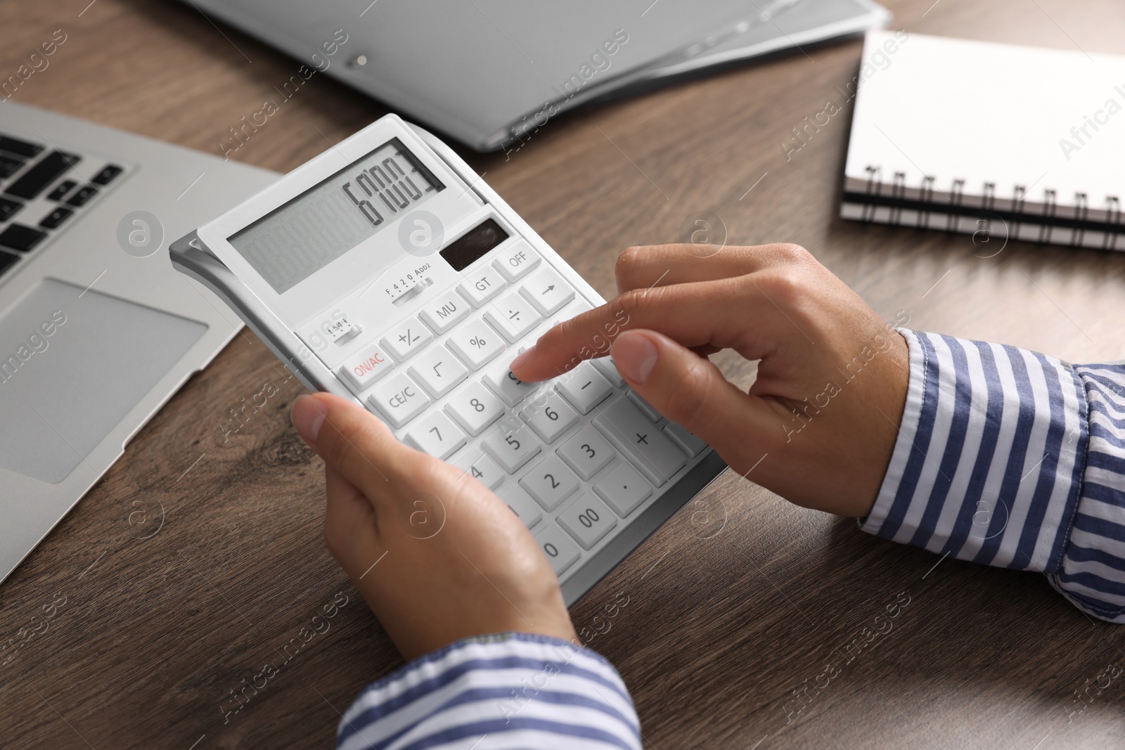 Photo of Woman using calculator at wooden table, closeup