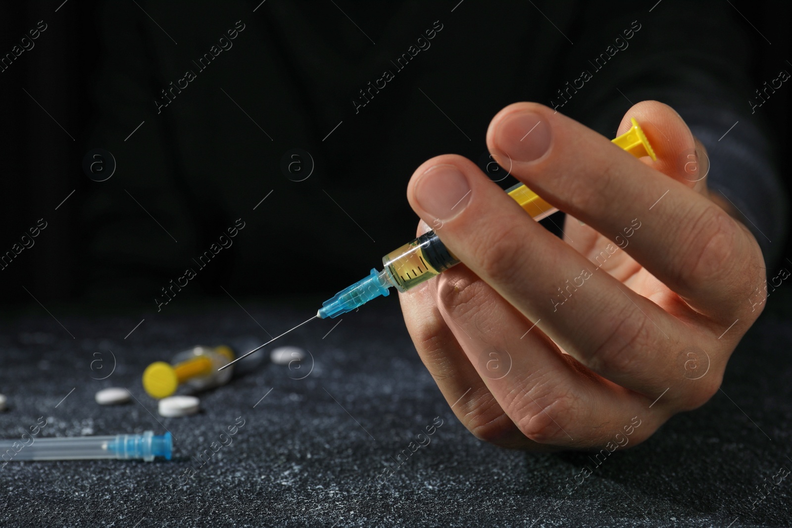 Photo of Drug addiction. Man with syringe on black textured table, closeup and space for text