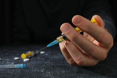 Drug addiction. Man with syringe on black textured table, closeup and space for text