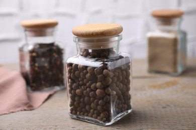 Glass jar with peppercorns on wooden table