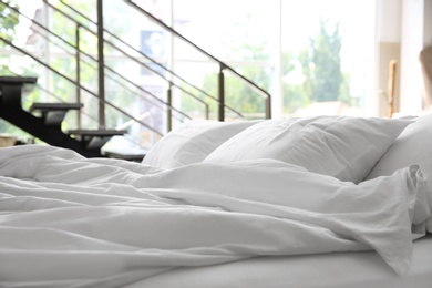 Soft white pillows on messy bed, closeup