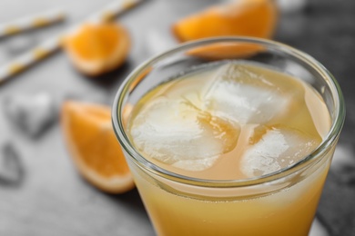 Glass of orange juice with ice cubes on table, closeup. Space for text