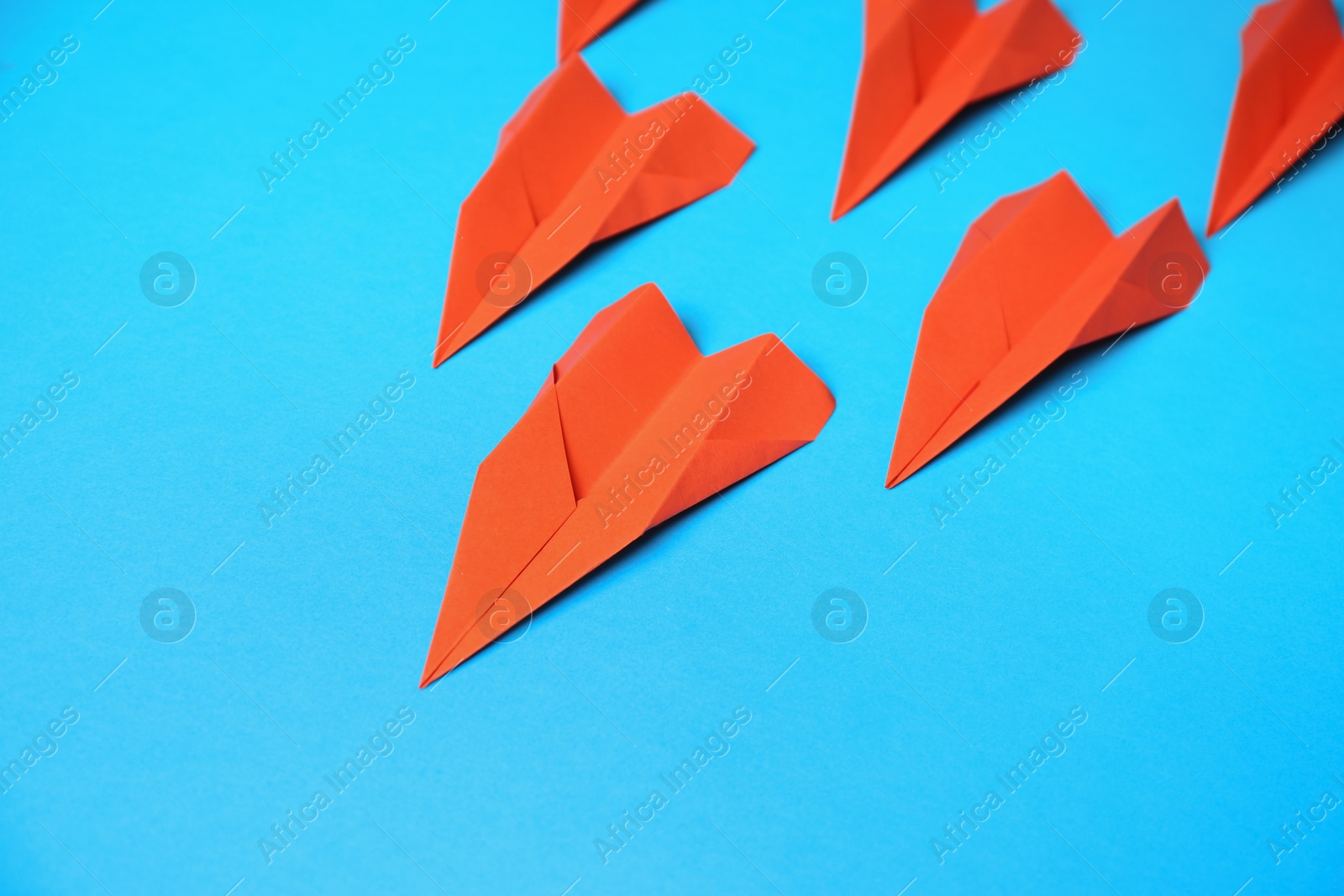 Photo of Many red paper planes on light blue background, above view