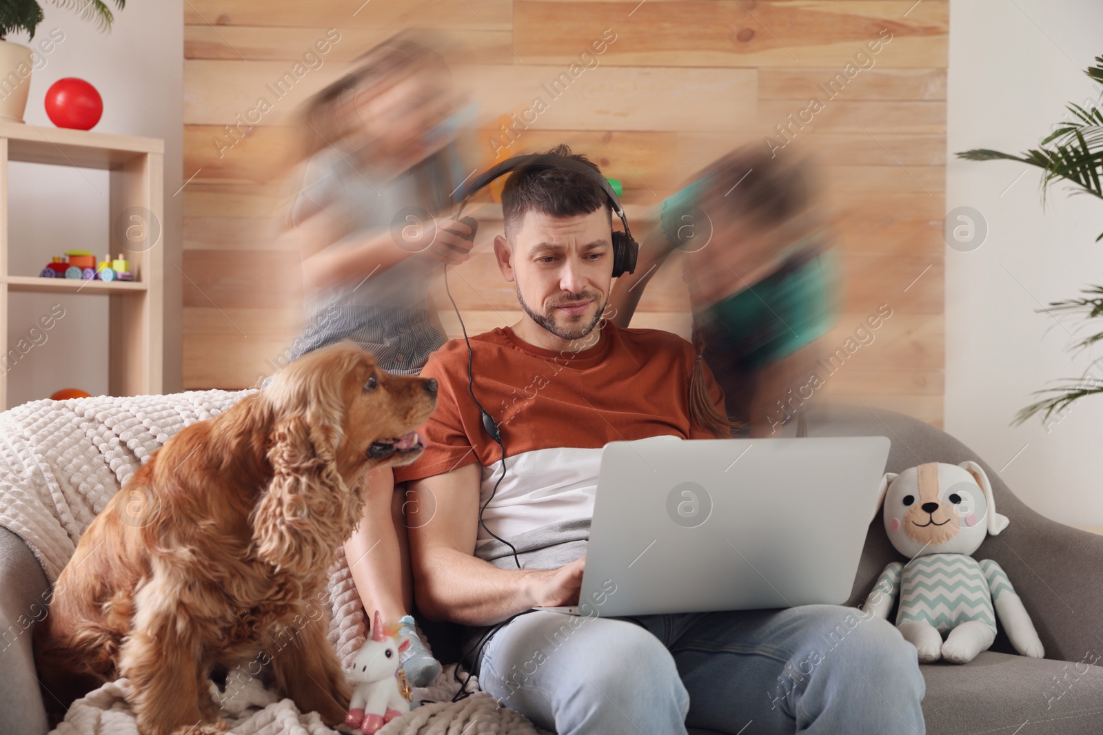 Image of Children disturbing overwhelmed man in living room. Working from home during quarantine