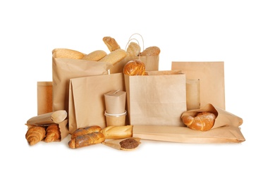 Different fresh bakery products in paper bags on white background