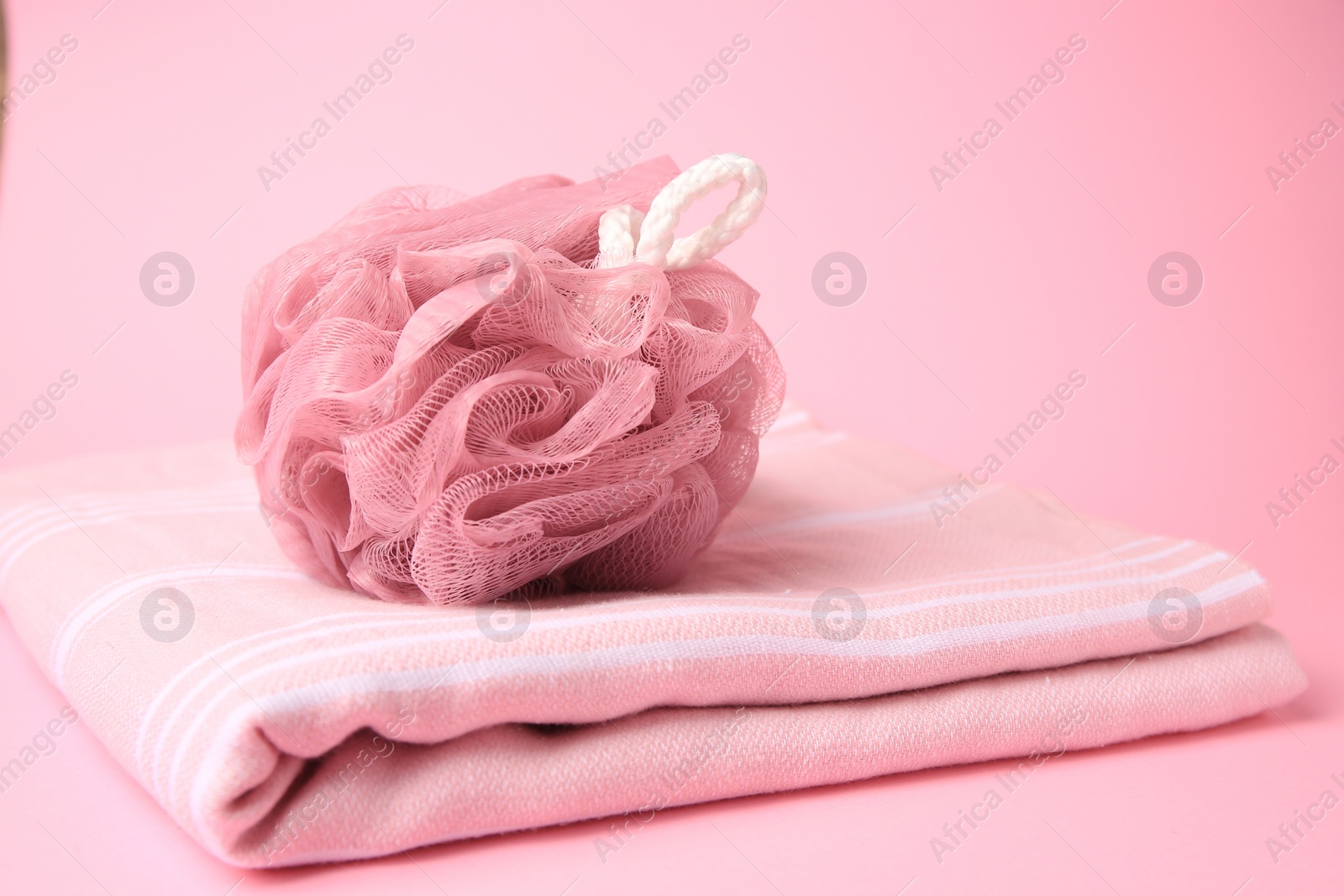 Photo of Shower puff with towel on pink background