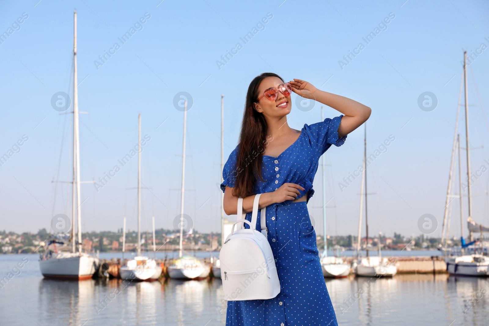 Photo of Beautiful young woman with stylish backpack near river