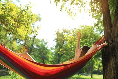 Photo of Young woman resting in comfortable hammock at green garden