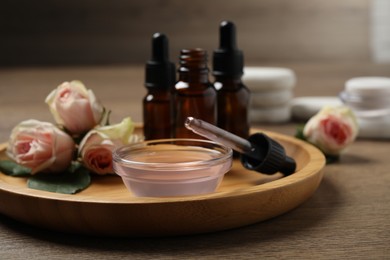 Photo of Rose essential oil and flowers on wooden table