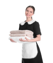 Young chambermaid holding stack of fresh towels on white background