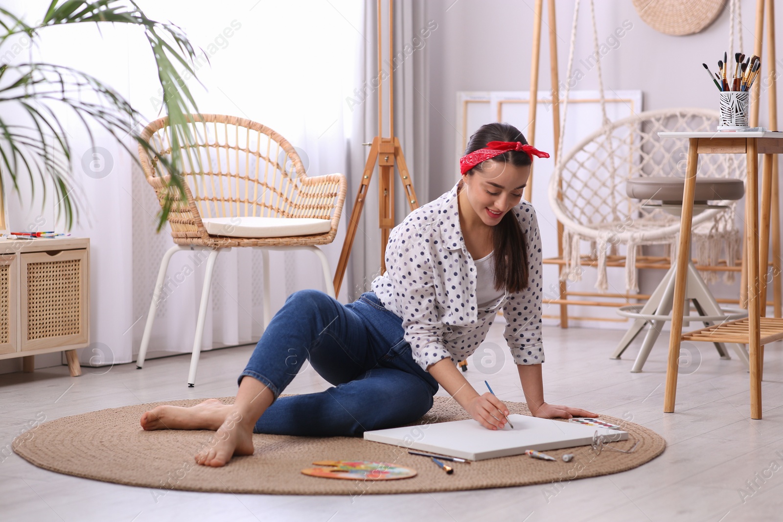 Photo of Happy woman artist drawing picture on canvas in studio