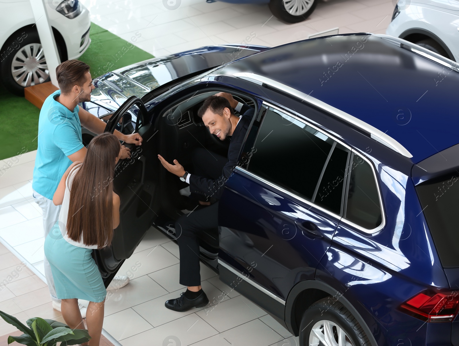 Photo of Salesman consulting young couple in car salon