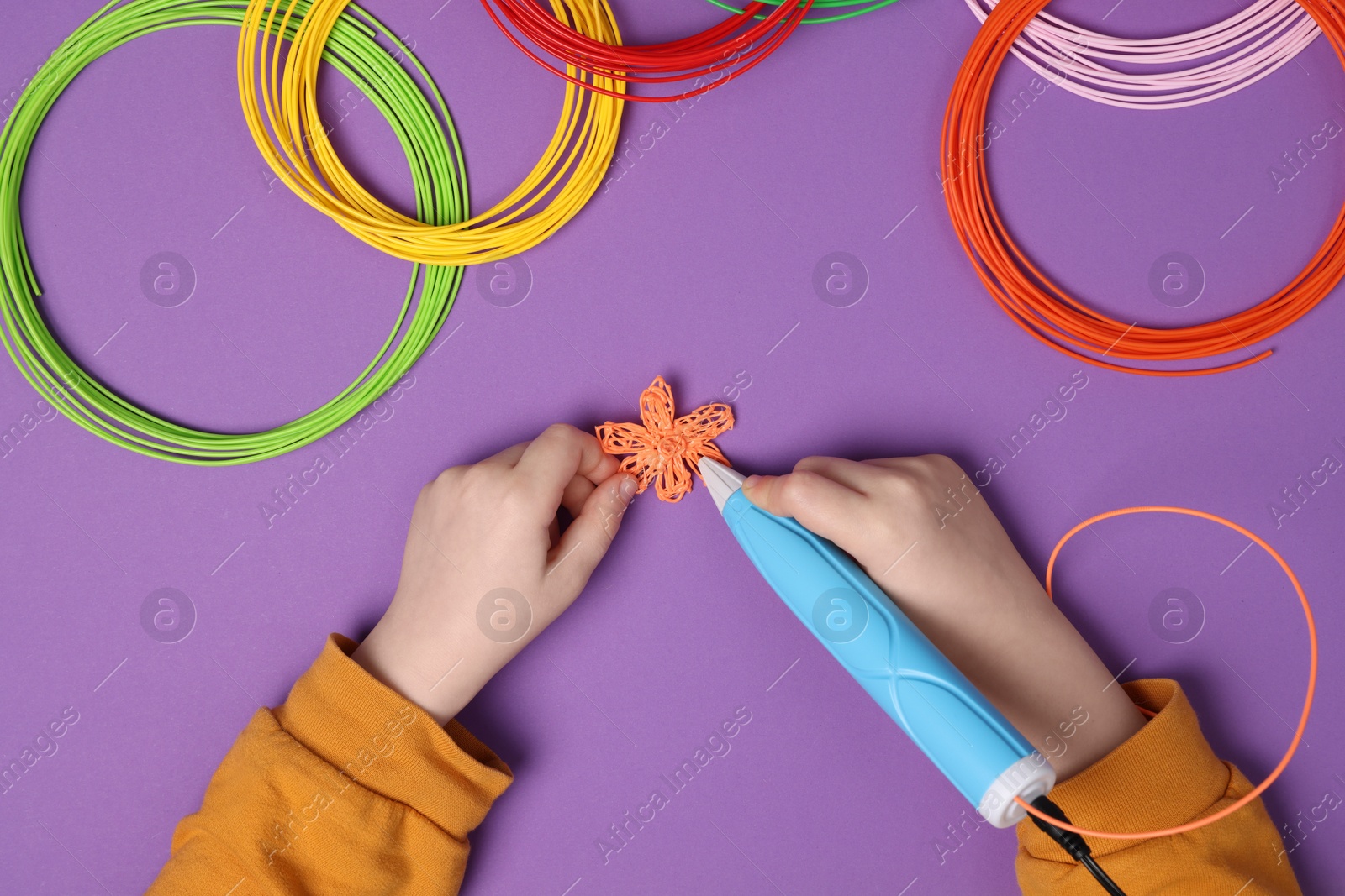 Photo of Boy drawing with stylish 3D pen on purple background, top view