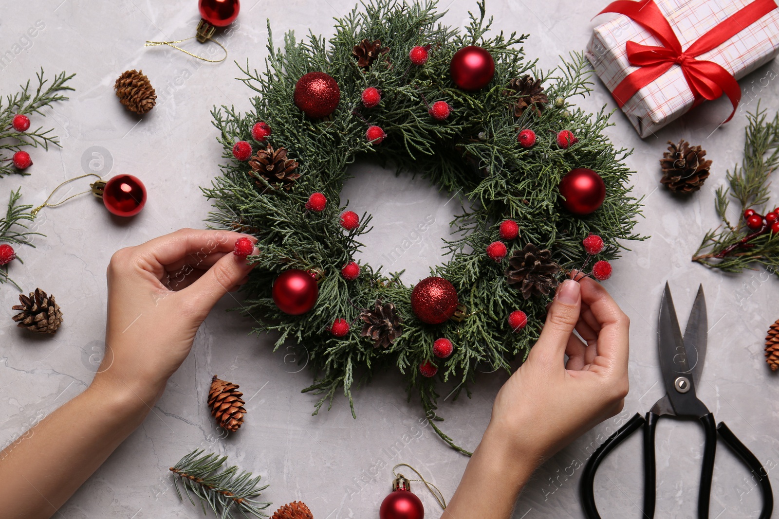 Photo of Florist making beautiful Christmas wreath at grey table, top view