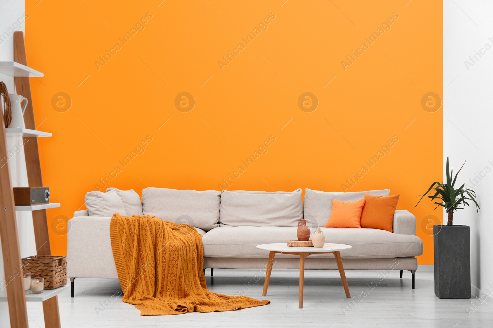 Photo of Stylish sofa and coffee table in room with orange walls. Interior design