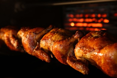 Photo of Grilling whole chickens in rotisserie machine, closeup