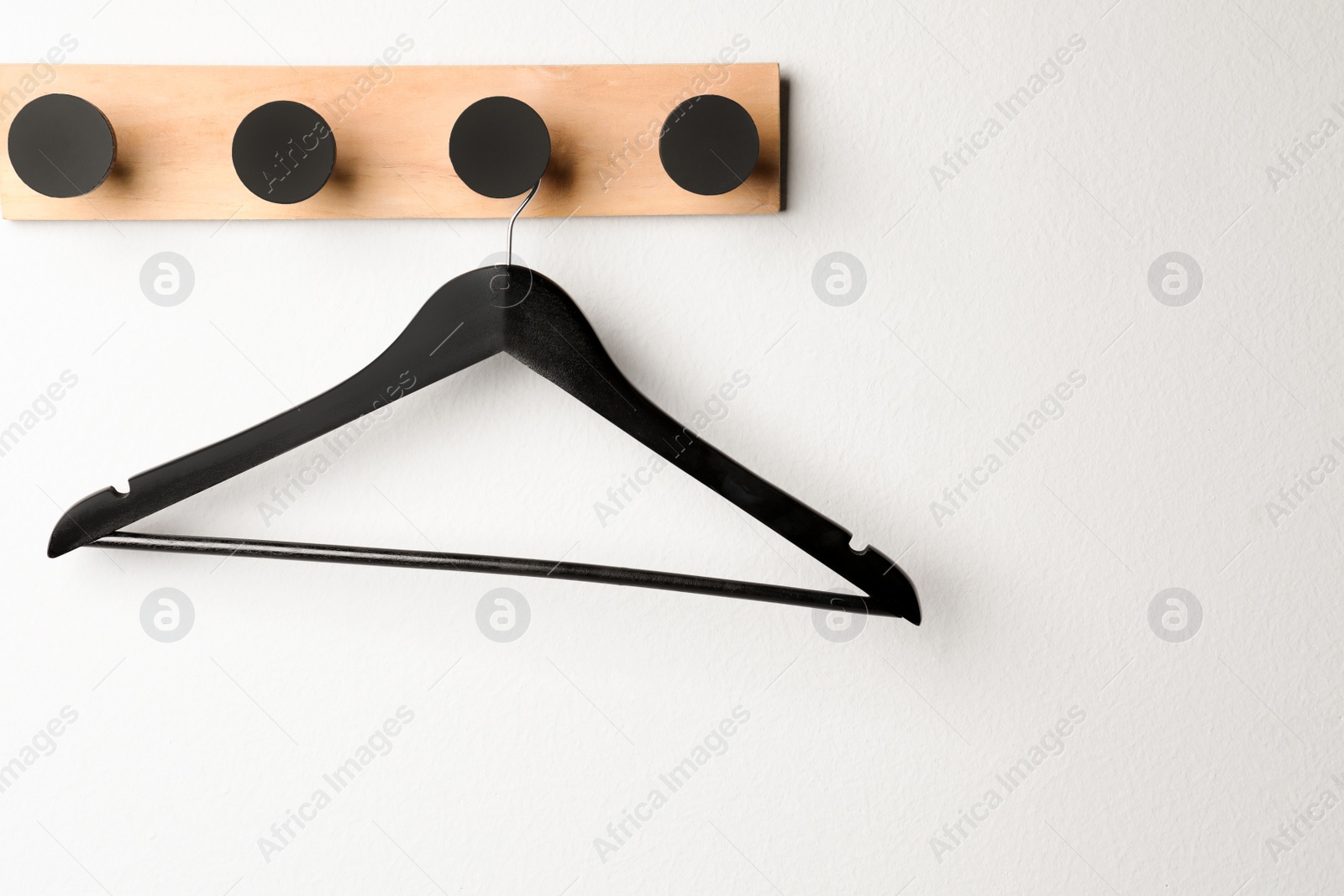 Photo of Rack with empty black clothes hanger on white wall