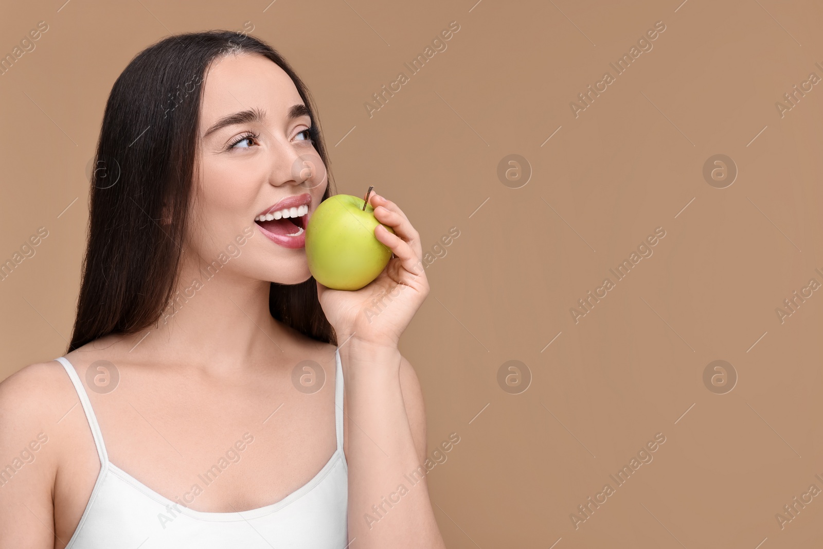 Photo of Beautiful young woman with apple on beige background. Space for text