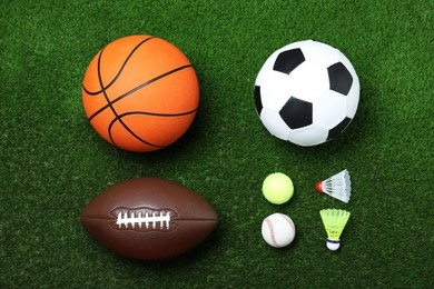 Set of different sport balls and shuttlecocks on green grass, flat lay