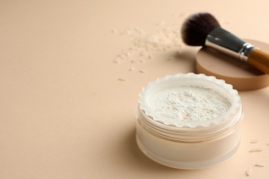 Photo of Rice loose face powder and makeup brush on beige background, closeup. Space for text