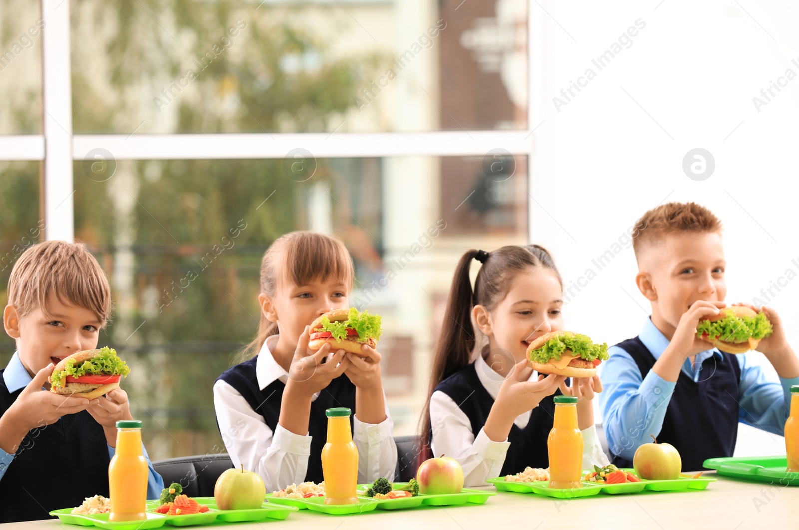 Photo of Happy children eating healthy food for lunch in school canteen