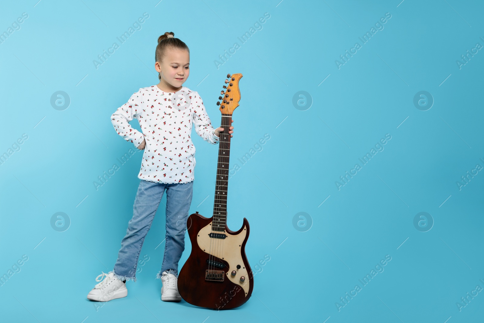 Photo of Happy girl with electric guitar on turquoise background. Space for text