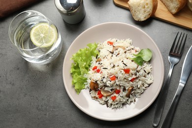 Photo of Delicious rice pilaf with mushrooms served on grey table, flat lay