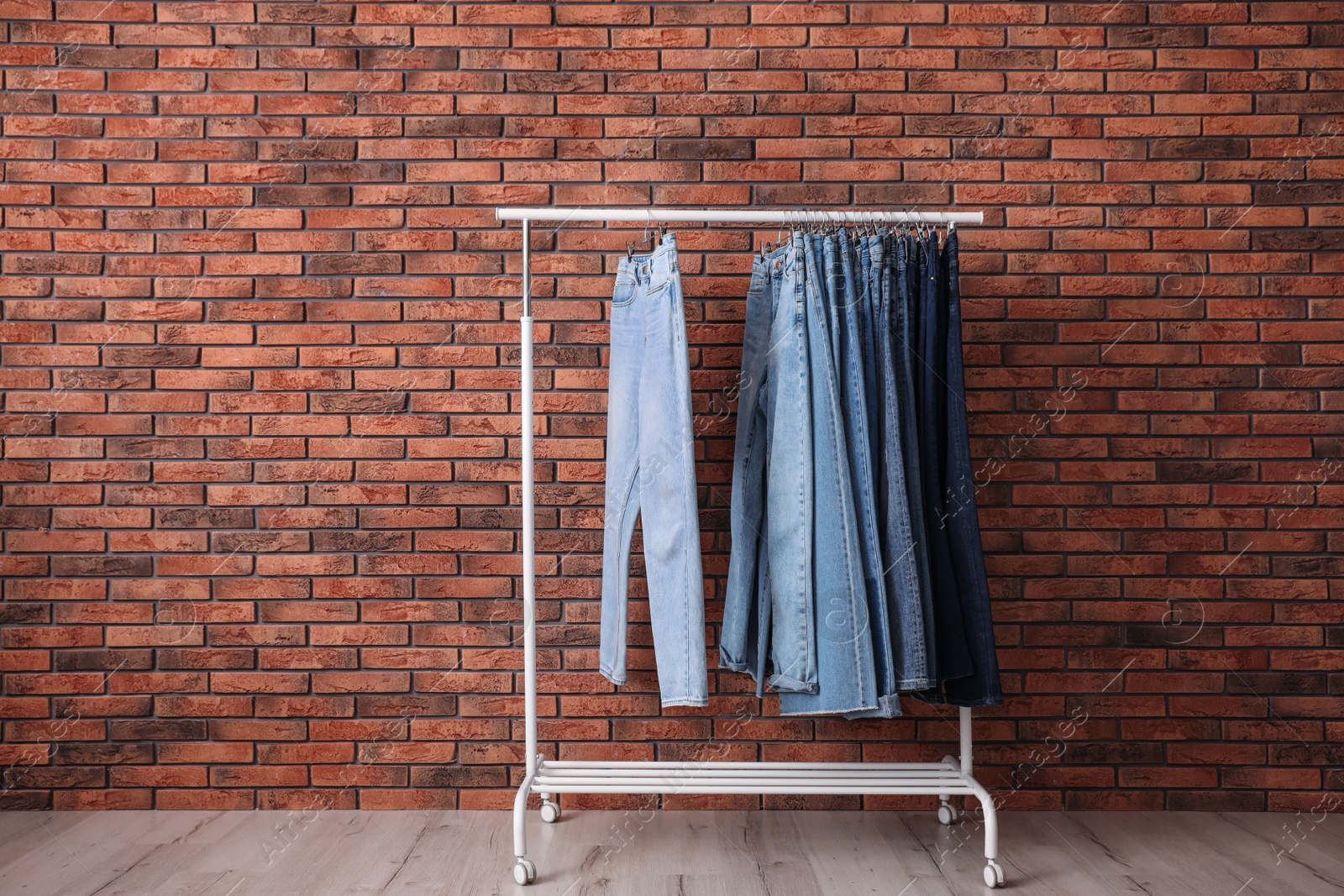 Photo of Rack with stylish jeans near brick wall