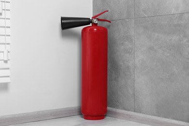 Photo of Red fire extinguisher on floor in corner