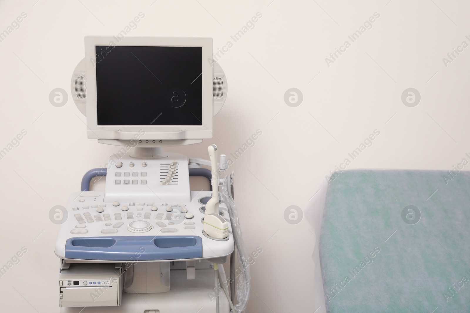 Photo of Ultrasound machine near white wall. Medical equipment