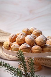 Photo of Delicious nut shaped cookies and fir tree branch on table