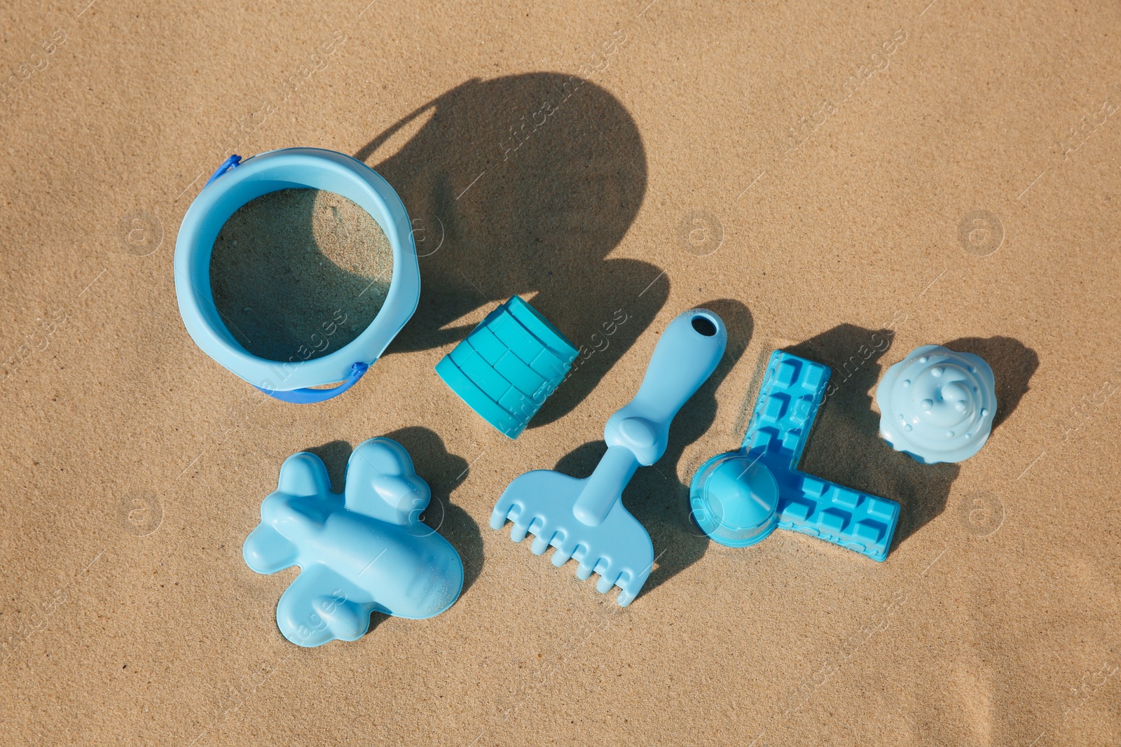 Photo of Set of plastic beach toys on sand, flat lay. Outdoor play