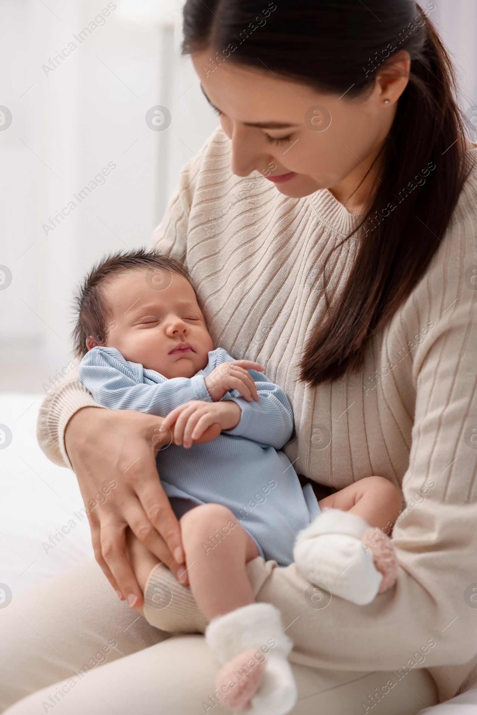 Photo of Mother with her sleeping newborn baby indoors