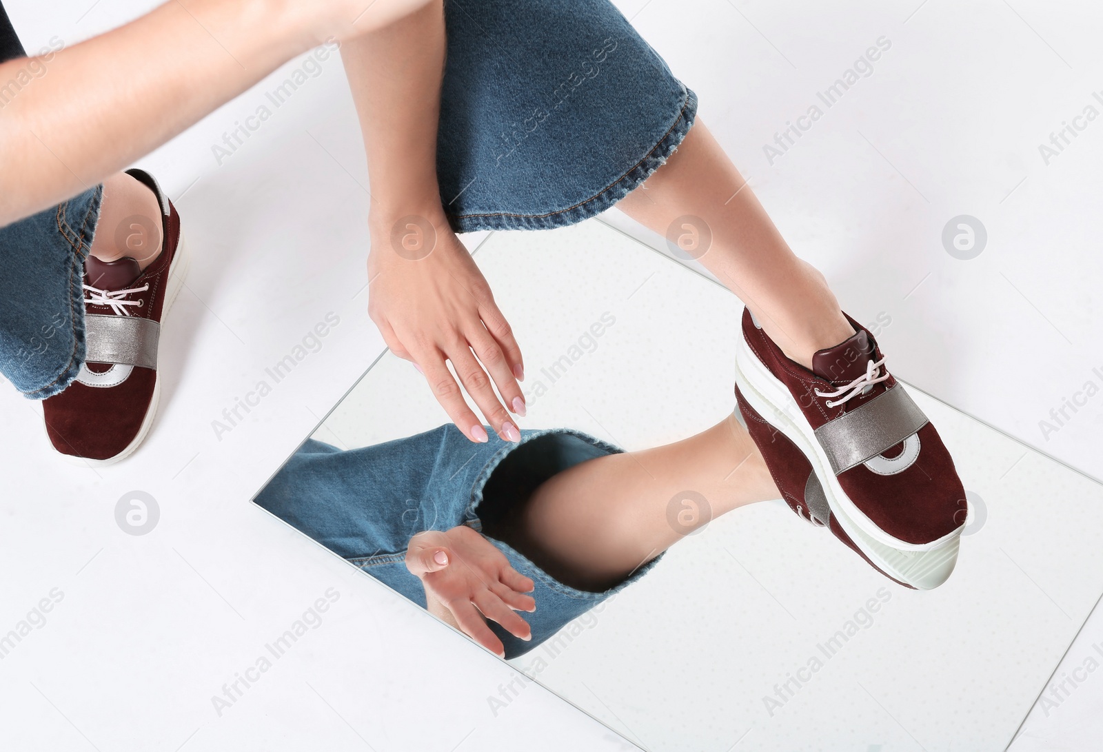 Photo of Woman in stylish shoes standing on mirror, white background