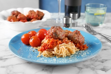 Delicious pasta with meatballs and tomato sauce on table