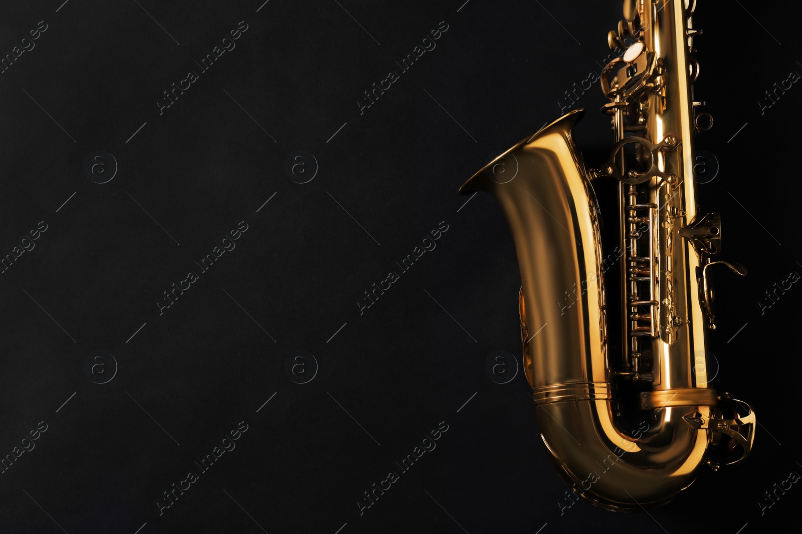 Photo of Beautiful saxophone on black background, top view. Space for text