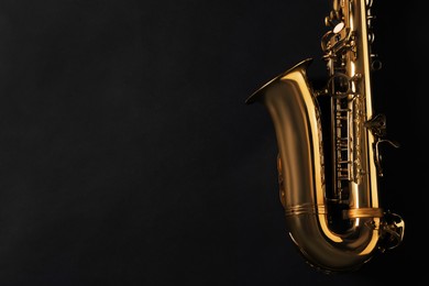 Beautiful saxophone on black background, top view. Space for text