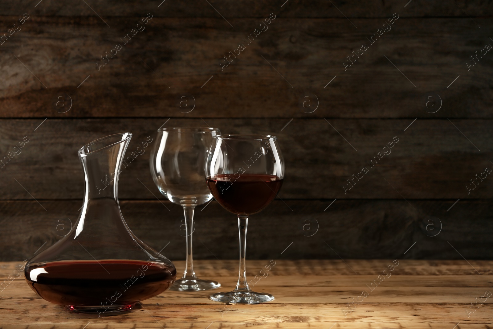 Photo of Elegant decanter with red wine and glasses on wooden table