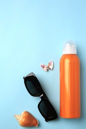 Bottle of sunscreen, sunglasses and seashells on light blue background, flat lay. Space for text